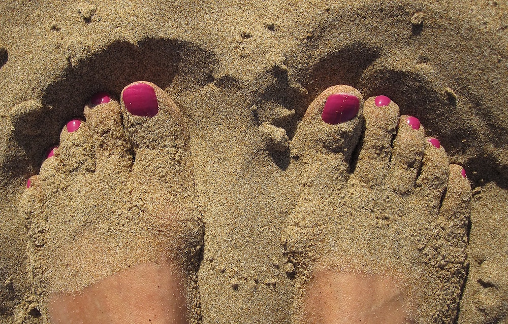 cuida tus pies en verano, consejos de tu podologo de parla, pies en arena de playa